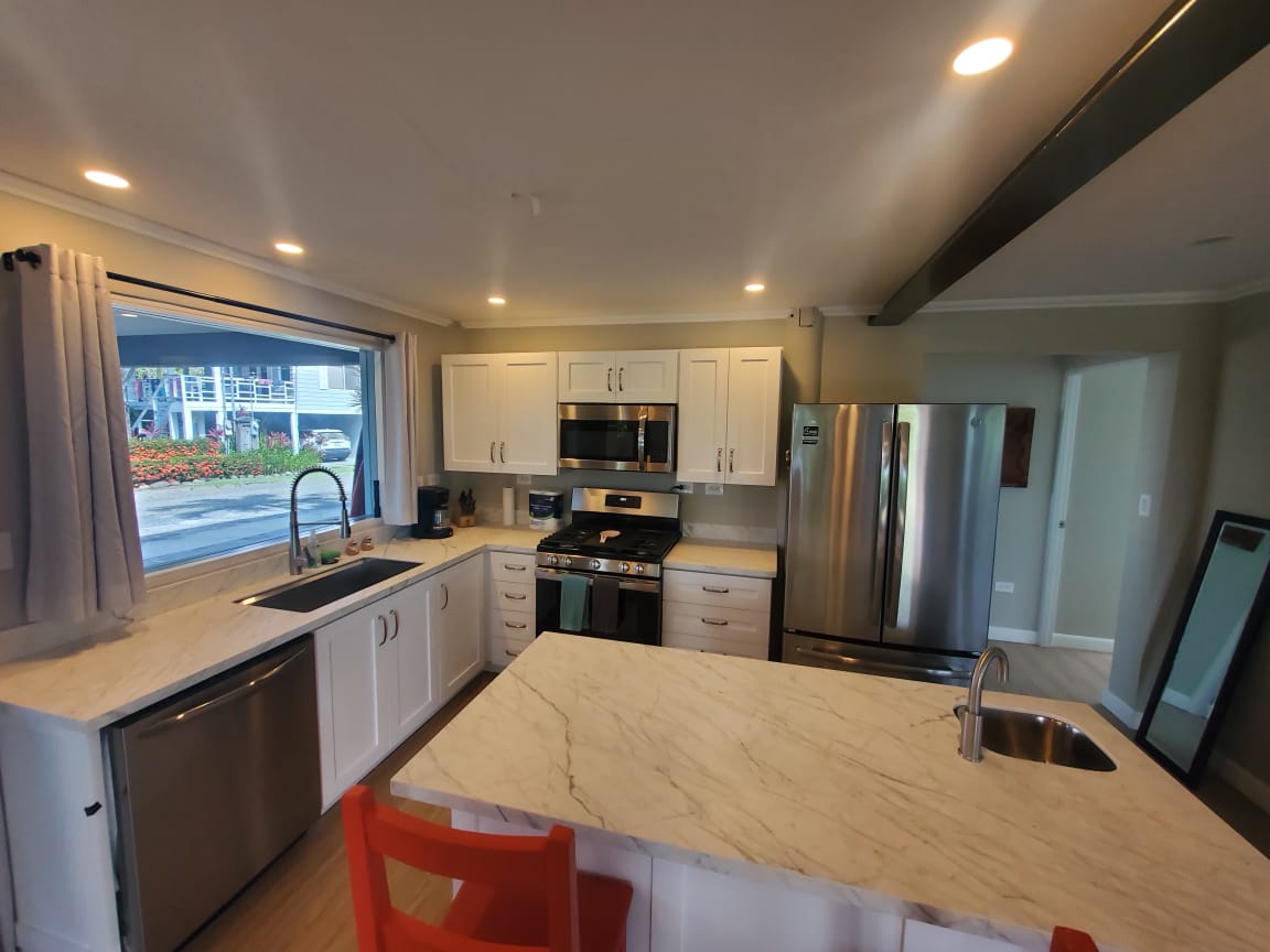 Full kitchen with island, red bar stools and stainless appliances