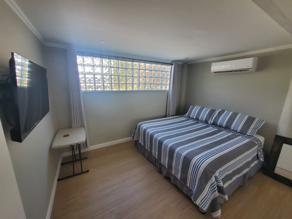 Bedroom with queen bed, TV and glass block window