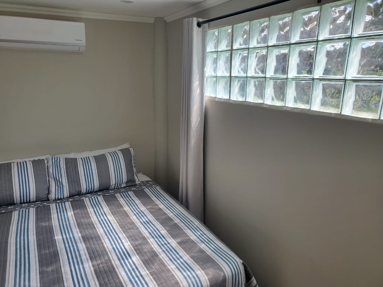 Small bedroom with glass block window and AC
